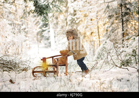 Ein vier Jahre alter Junge spielt im Winter, verschneiten Wald Stockfoto