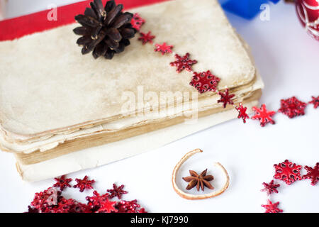 Altes Buch und Weihnachten dekoriert, mit Kegel auf weißen Tisch aufgetürmt. Stockfoto