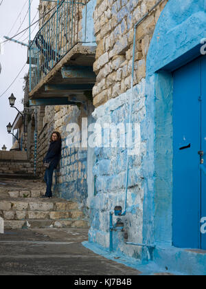 Frau, die auf einer Steinmauer in der Straße, Safed, Nordbezirk, Israel, lehnt Stockfoto