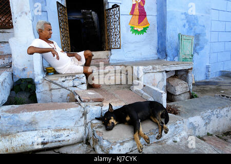 Alte indische Mann in Weiß auf der Treppe sitzt mit seinem Hund vor seinem Haus, Jodhpur, Rajasthan, Indien gekleidet. Stockfoto