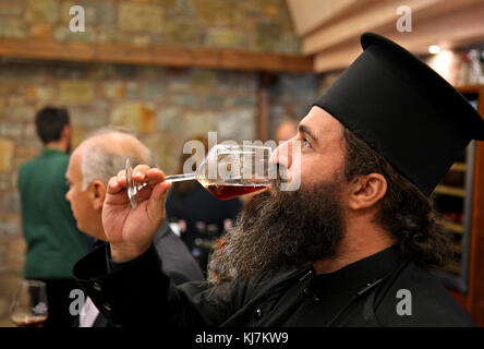 Griechisch-orthodoxer Priester, der in der Weinkellerei des Klosters Toplou, in der Nähe des berühmten Strandes von Vai, Sitia, der Präfektur Lasithi, Kreta, Griechenland, Rotwein verkostet. Stockfoto