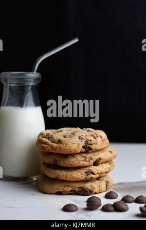 Gestapelte Chocolate Chip Cookies und Milch in einem vintage Flasche mit Strohhalm Stockfoto