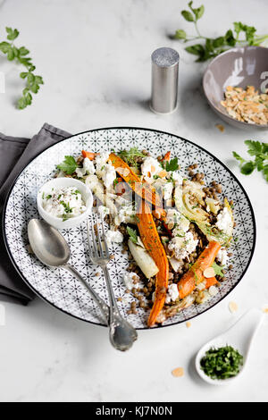 Linsensalat mit gerösteten Karotte, Fenchel, Mandeln und Feta Käse auf weißer Tisch. Helle Stimmung Stockfoto