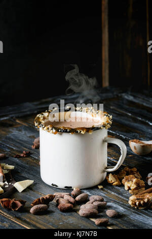 Vintage Tasse heiße Schokolade, Einrichtung mit Muttern, Karamell, Gewürze. Zutaten oben. Gehackte dunkle und weiße Schokolade, Kakao, Anis über alte Woode Stockfoto