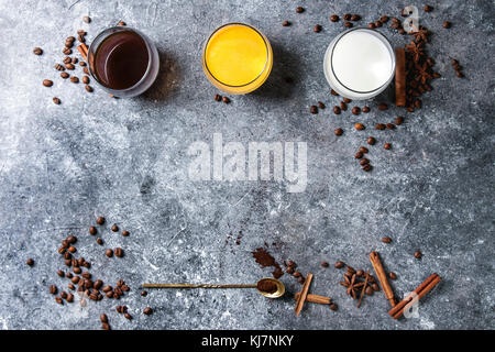 Zutaten für Cook würziger Kürbis latte. Brille mit schwarzem Kaffee, Kürbis Milch, Sahne mit Gewürzen, Kaffeebohnen und dekorative Kürbisse oben über Stockfoto