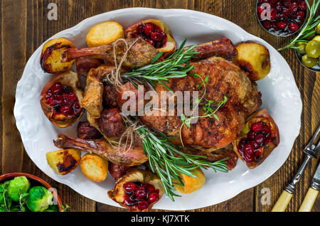 Festliche gebratene Ente mit Rosenkohl, Preiselbeersoße und Bratkartoffeln auf Holztisch - Ansicht von oben Stockfoto