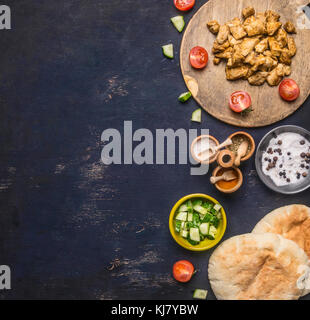 Zutaten zum Kochen von hausgemachten Shawarma, gebratenes Huhn mit Gewürzen, Pita, in Scheiben geschnittene Gurken, Gewürze Gewürze, auf Holz rustikale Hintergrund Stockfoto