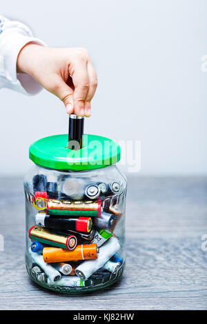 Kid Hand füllen Sie das Glas mit AA- und AAA-Akkus Stockfoto