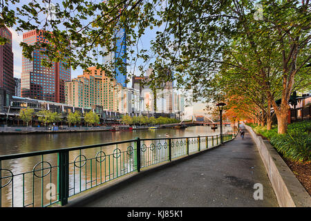 Fussweg entlang den Fluss Yarra in Melbourne downtown unter schattigen Bäumen mit Blick auf die southbank und Walker Brücke in den frühen Morgen. Stockfoto