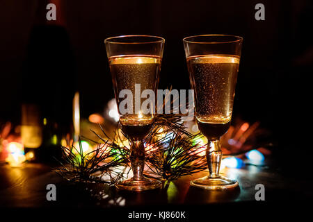 Champagner im Glas, Weihnachten oder die Zusammensetzung des neuen Jahres mit Tannenzweigen, Tannenzapfen und brennende bunte Girlande, vintage Holz- Hintergrund, selec Stockfoto