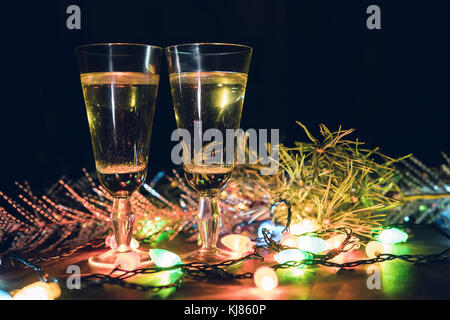 Zwei Gläser mit Champagner auf einem Holztisch mit Weihnachten Zubehör eingerichtet das neue Jahr und Weihnachten zu feiern. romantischen Abend. Die Glühkerzen Stockfoto