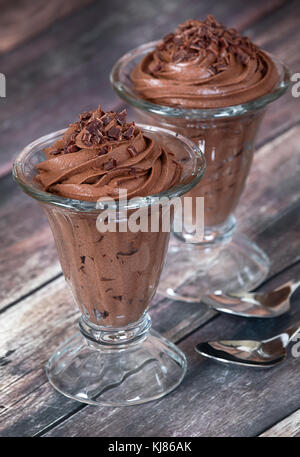 Dunkle Mousse au chocolat Dessert im Glas serviert Schalen. rustikalen Holztisch Hintergrund. Stockfoto