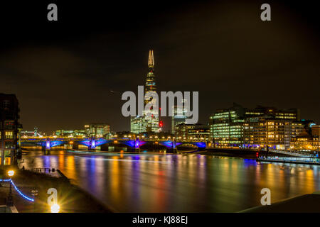 Reflexionen in der Themse, London, England Europa bei Nacht in Richtung der Shard und London Dachfenster suchen beleuchtet die Southwark Bridge Stockfoto