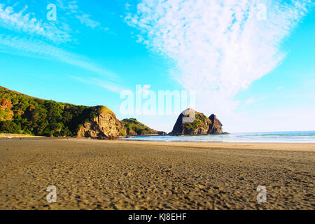 Einen malerischen Sonnenuntergang an der Piha Beach mit Felsformationen im Hintergrund Stockfoto