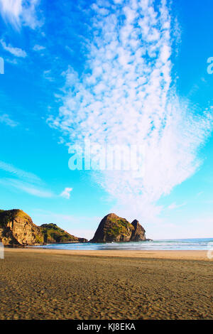 Einen malerischen Sonnenuntergang an der Piha Beach mit Felsformationen im Hintergrund Stockfoto