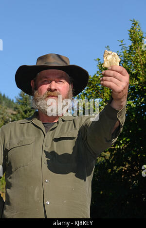 Ein Prospektor hält ein Exemplar einer Gold Nugget. Fokus auf der prospektor Gesicht. Stockfoto