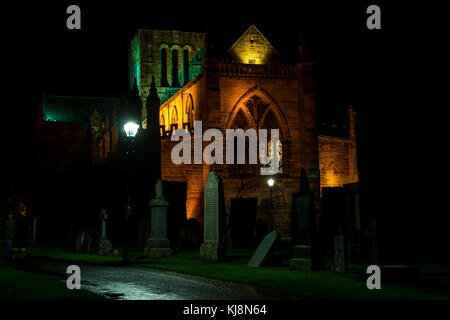 St Mary's Stiftskirche, Haddington, East Lothian, Schottland, Großbritannien, in der Nacht mit Grabsteinen und Friedhof, und große beleuchtete Fenster aus buntem Glas. Stockfoto