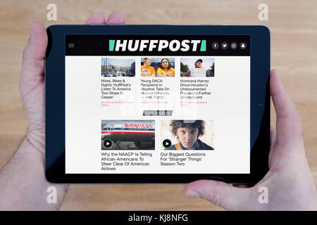 Ein Mann schaut auf die Huffington Post Website auf seinem iPad tablet device, Schuß gegen einen hölzernen Tisch top Hintergrund (nur redaktionelle Nutzung) Stockfoto
