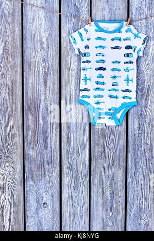 Jungen gemusterten Bodysuit hängend am Seil. baby boy Soft romper Trocknen auf der Wäscheleine auf hölzernen Hintergrund, kopieren. Stockfoto