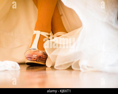 Die Braut hat ein Auto auf dem Schuh und sitzt auf einem Stuhl Stockfoto