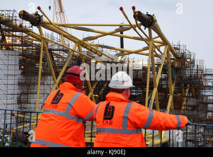 Die Arbeit an Windturbinenjacken geht weiter, während die Arbeiter von einer Aussichtsplattform vor einem Besuch von First Minister Nicola Sturgeon in Burntisland Fabrications Ltd (BiFab) in Methil in Fife schauen. Stockfoto