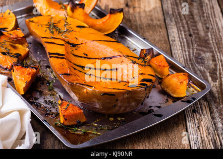 Gebratener Kürbis mit Thymian und Balsamico auf der Oberseite über rustikalen Holztisch Glasur, Herbst gemütliche Dish Stockfoto