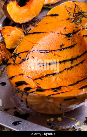 Gebratener Kürbis mit Thymian und Balsamico auf der Oberseite über rustikalen Holztisch Glasur, Herbst gemütliche Dish Stockfoto