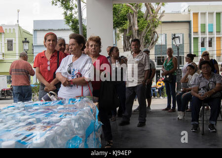 SAN JUAN, Puerto Rico - Bewohner warten FEMA Disaster survivor Hilfe Spezialisten zu sehen und Essen und Wasser in Bayamon, Nov. 14, 2017 sammeln. Fast zwei Monate nach dem Sturm, einige Einheimische verlassen sich immer noch auf die Versorgung durch die Regierung für Unterhalt zur Verfügung. (US Army Foto von SPC. Samuel D. Keenan) Stockfoto