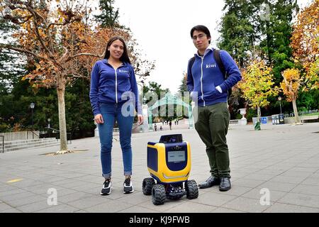 Berkeley, Kalifornien, USA. November 2017. Camila Reino und David Cardozo Mitglieder eines Teams aus Columbia stehen neben einem Kiwi On-Demand-Lieferroboter vor Sather Gate an der University of California Berkeley. Kredit: Rory Merry/ZUMA Wire/Alamy Live News Stockfoto