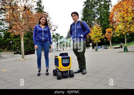 Berkeley, Kalifornien, USA. November 2017. Camila Reino und David Cardozo Mitglieder eines Teams aus Columbia stehen neben einem Kiwi On-Demand-Lieferroboter vor Sather Gate an der University of California Berkeley. Kredit: Rory Merry/ZUMA Wire/Alamy Live News Stockfoto