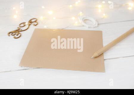 Weihnachten mock up Kraftpapier und Bleistift mit Platz für Ihren Text und White christmas garland auf weißem Holz- Hintergrund Stockfoto