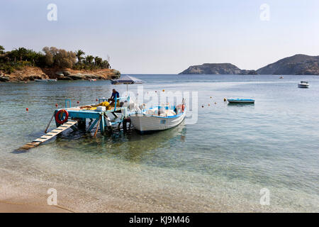 Bucht von Agia Pelagia, wo ein Fischer seine Netze in der Nähe des Strandes auf der Insel Kreta in Griechenland repariert Stockfoto