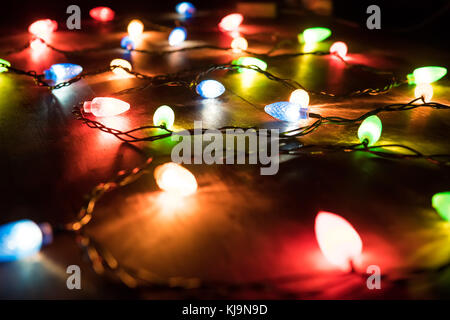 Das Licht der bunten Lichtern der Girlande in der Dunkelheit. farbige Lichter auf einem weihnachtsgirlande in der Dunkelheit der Nacht Stockfoto