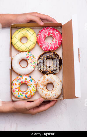 Farbige Donuts mit Glasur. versch. Donuts mit verschiedenen Füllungen in der Box Stockfoto