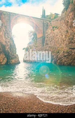 Wunderschönen Kiesstrand mit Blick auf die Alte Brücke bei Sonnenuntergang mit Sonne durch am fiordo di Sorrento, Amalfi Küste, Italien Stockfoto