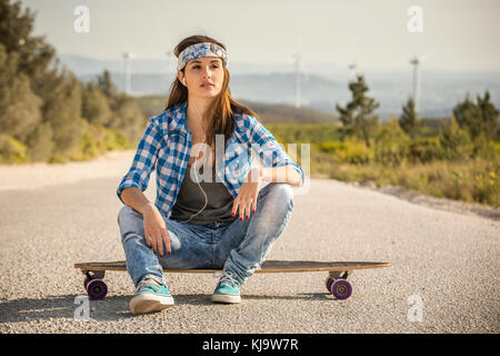 Schöne junge Frau sitzt auf einem skateboard Stockfoto