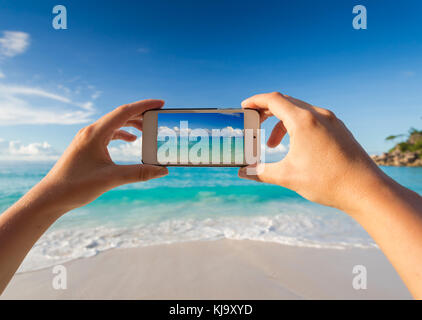 Weibliche Hände ein Bild von den Strand mit einem Mobiltelefon Stockfoto
