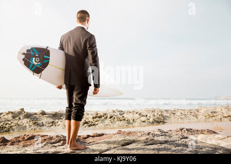 Der Unternehmer hält ist Surfbrett nach einem langen Tag der Arbeit Stockfoto