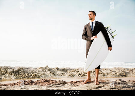 Der Unternehmer hält ist Surfbrett nach einem langen Tag der Arbeit Stockfoto