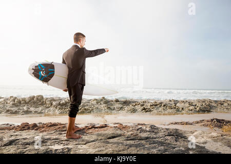 Der Unternehmer hält ist Surfbrett nach einem langen Tag der Arbeit Stockfoto