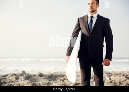 Der Unternehmer hält ist Surfbrett nach einem langen Tag der Arbeit Stockfoto