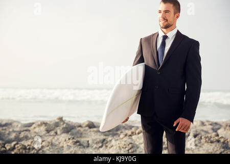 Der Unternehmer hält ist Surfbrett nach einem langen Tag der Arbeit Stockfoto