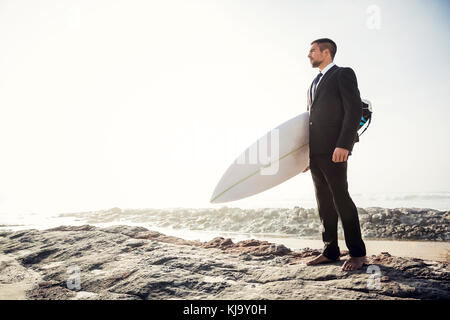 Der Unternehmer hält ist Surfbrett nach einem langen Tag der Arbeit Stockfoto