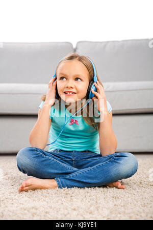 Kleine blondes Mädchen zu Hause hören Musik mit Kopfhörern Stockfoto