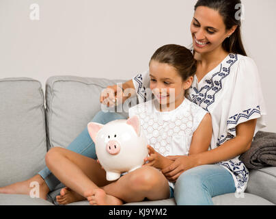 Mutter und Tochter Münzen in einem Sparschwein Stockfoto