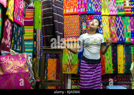 Myanmar (früher Birma). Yangon (Rangoon). Der Bogyoke Aung San Markt, der immer noch von seiner kolonialen Namen bekannt, Scott Markt. Frau in einem Textil shop Stockfoto