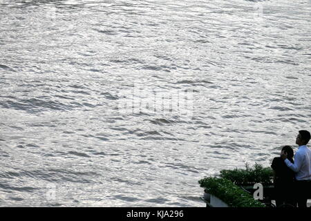 Ein paar schaut dem Chao Praya Fluss in der Dämmerung in Bangkok, Thailand. Stockfoto