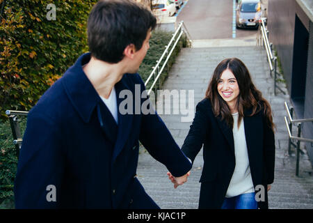 Schönes und glückliches Paar in Liebe Hände halten, während die Treppe im Freien Stockfoto