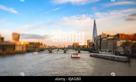 Anzeigen von Millennium Fußgängerbrücke in Richtung der Shard und Tower Bridge mit City Cruises Yacht Passing auf der Themse. Mit Tilt Shift Effekt. Stockfoto