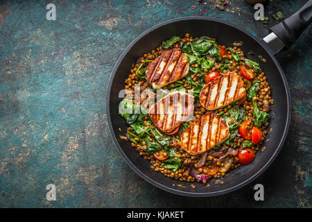 Vegetarisches Essen Konzept. Gesunde Linsengericht mit Spinat und gebratener Käse in der Küche pan auf rustikalen Hintergrund mit Zutaten, Ansicht von oben. Stockfoto